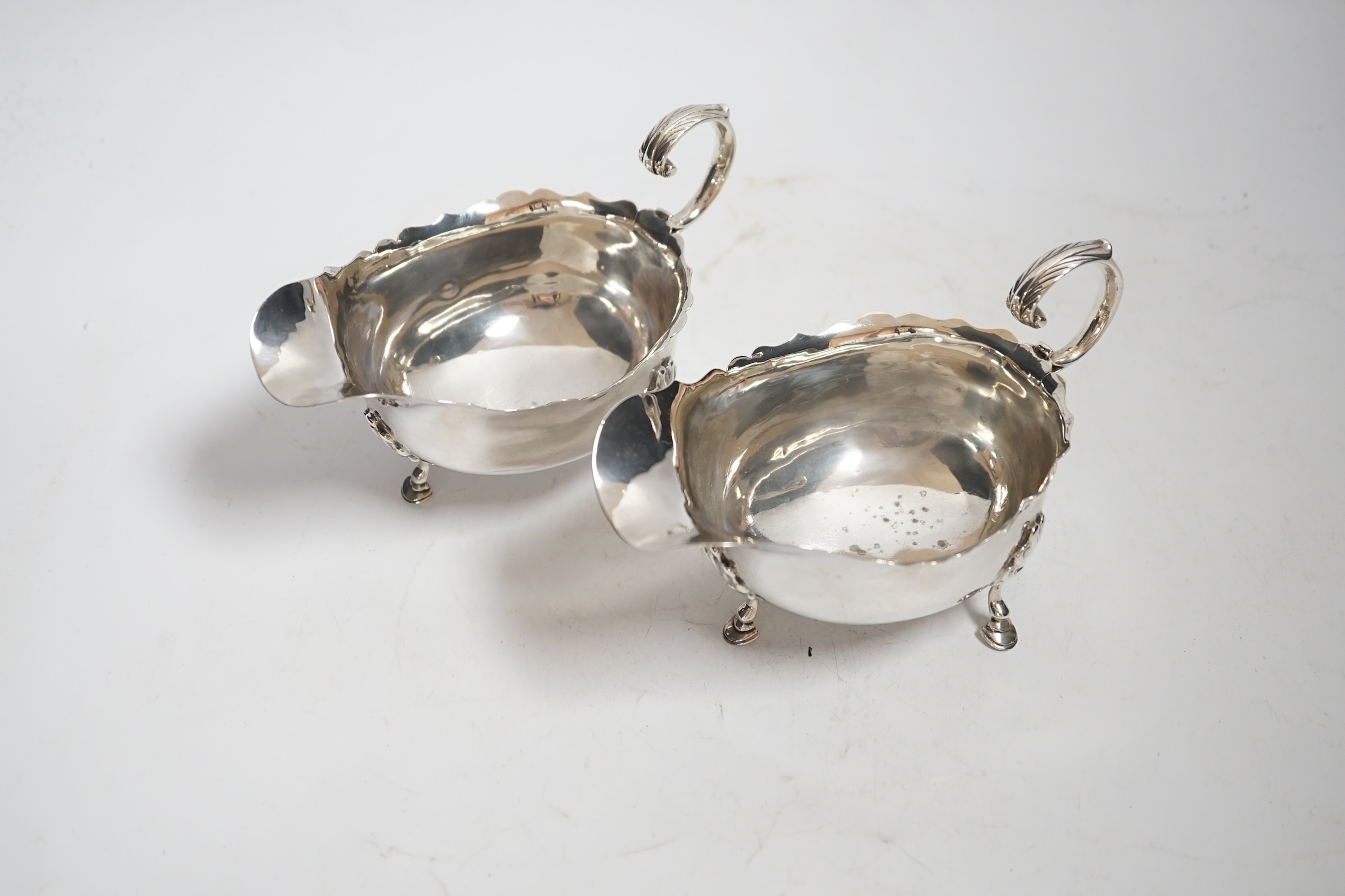 A pair of Edwardian silver sauce boats, with flying scroll handles, Nathan & Hayes, Chester, 1902, length 15.3cm, 9oz.